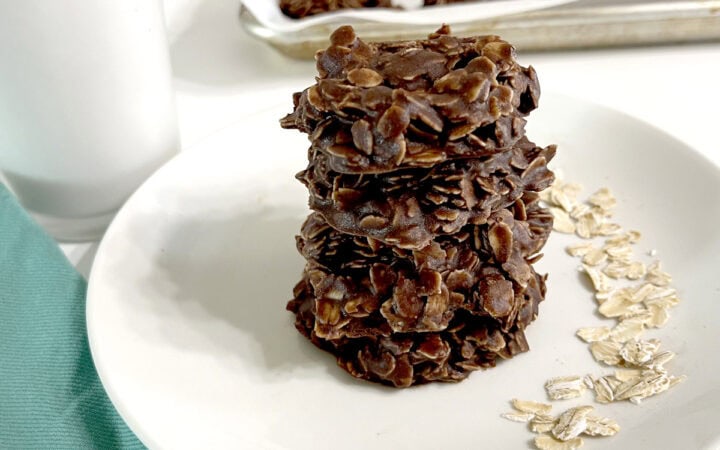 No Bake Cookies on white plate next to oats, milk, and on sheet pan
