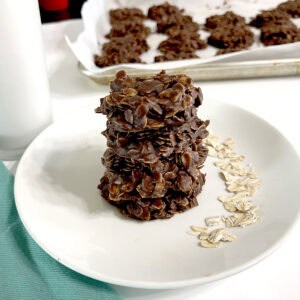 No Bake Cookies on white plate next to oats, milk, and on sheet pan