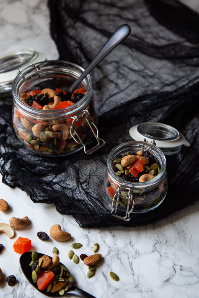 Healthy Halloween Trail Mix in jars and spooky setting.