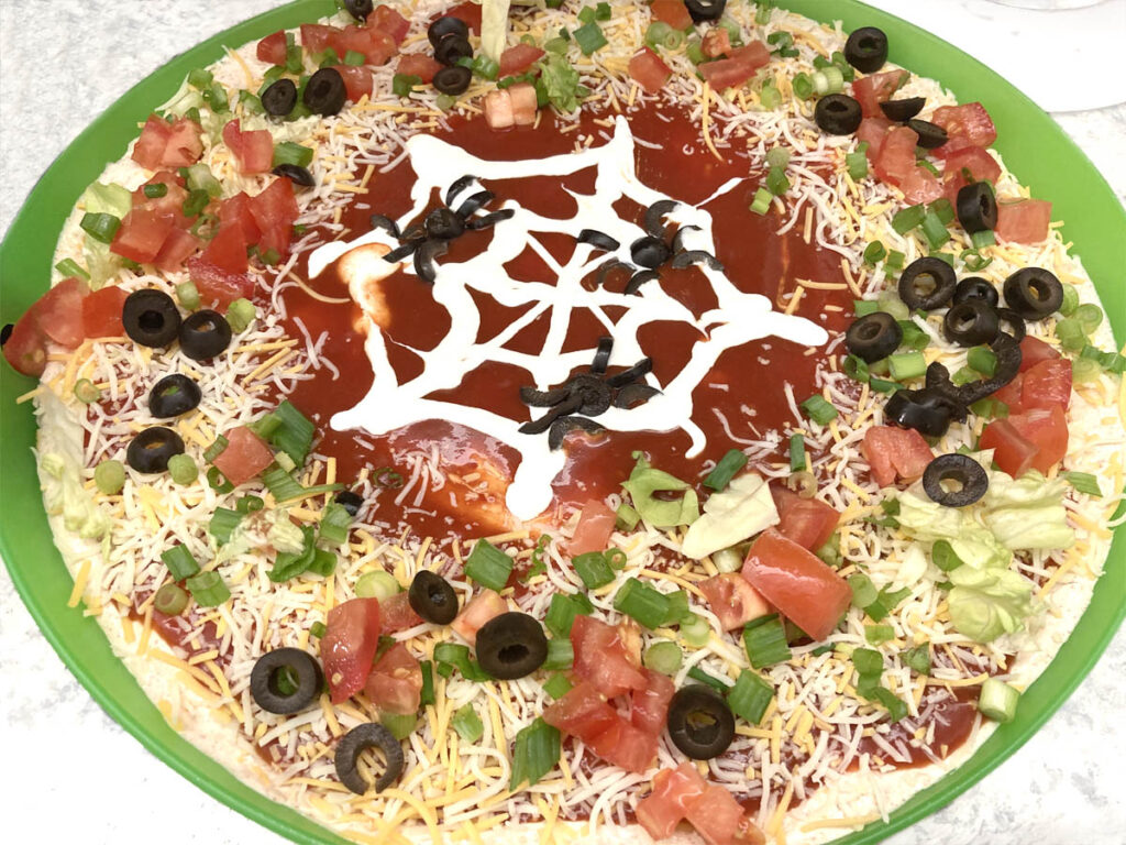 Healthy taco dip for party with spider design.