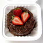 Easy chocolate bento cake design using chocolate frosting, chocolate shavings, and strawberries.