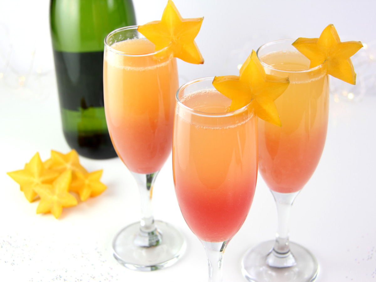 Hawaiian Sunrise Healthy Mimosas decorated with star fruit and low sugar champagne.