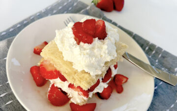 Gluten Free Strawberry Shortcake on plate with blue napkin and layers of cream and strawberries.
