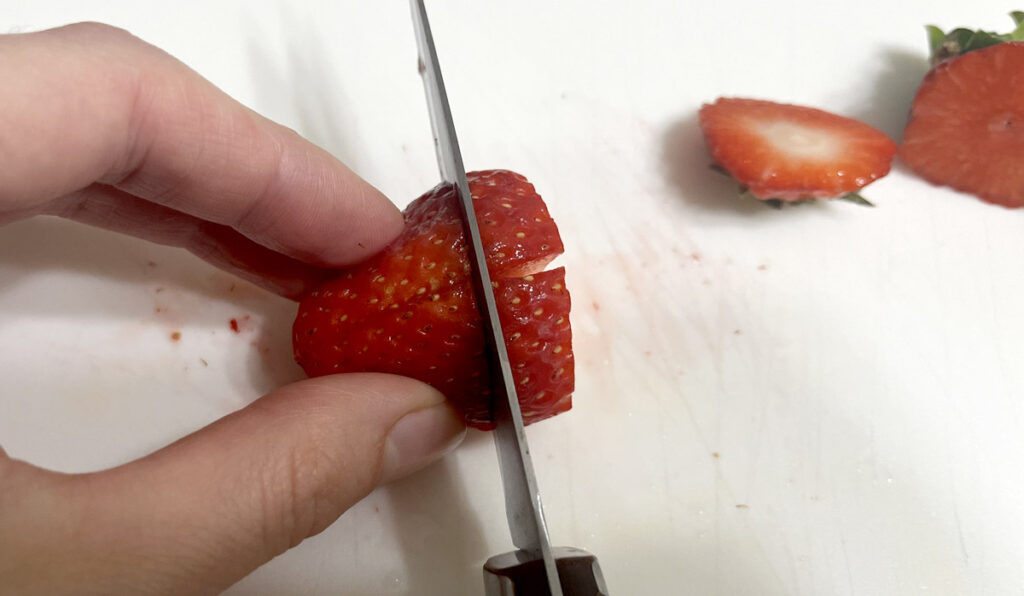 Cutting a strawberry: removing top, cutting in half, then cutting in half perpendicular.