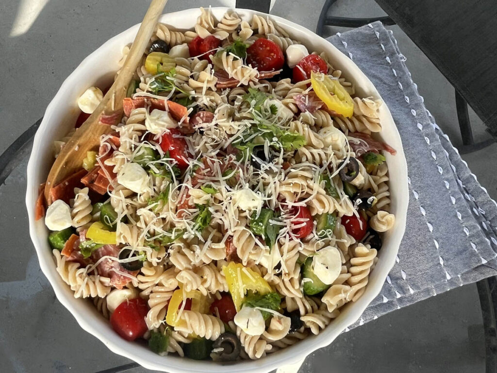 Gluten Free Pasta Salad served outside with wood spoon on blue napkin