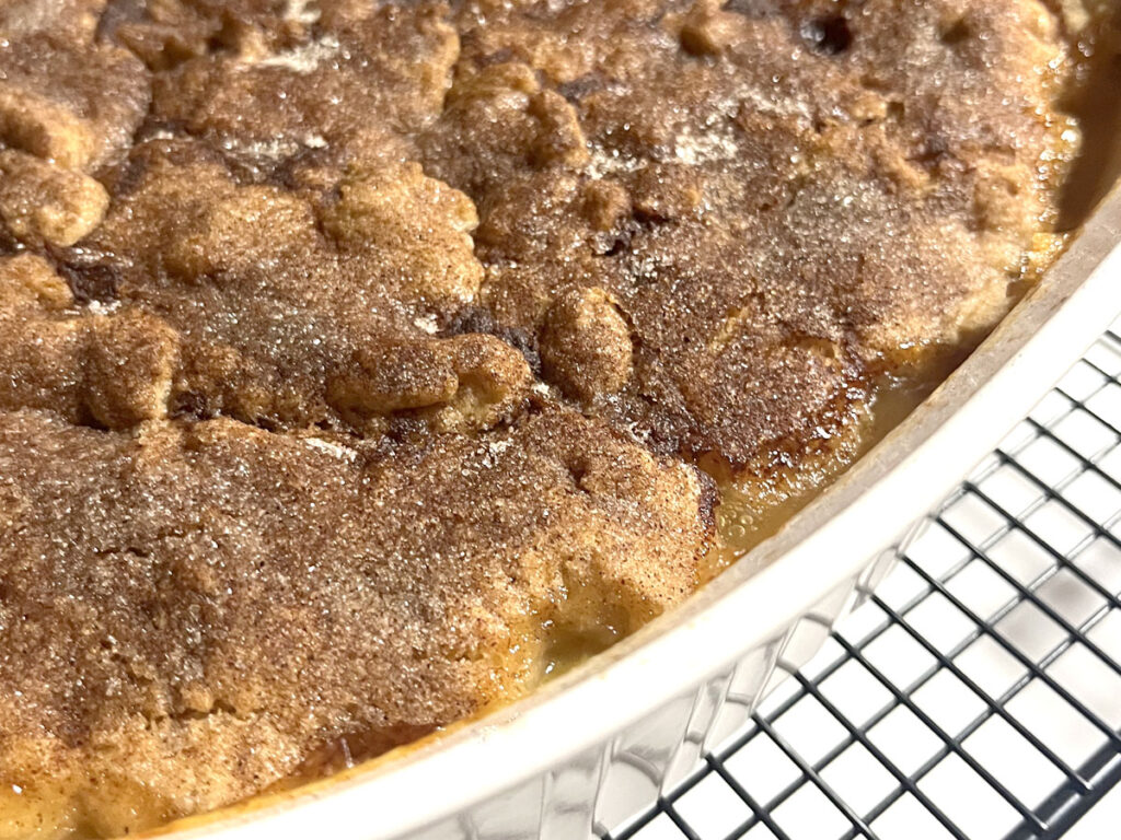 Easy Gluten Free Peach Cobbler in white dish on cooling rack