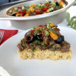 Cornbread Taco Bake slice on white plate with full pan in back