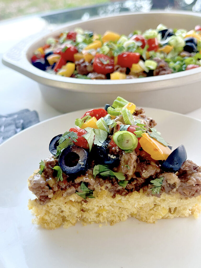 Cornbread Taco Bake slice on white plate with full pan in back