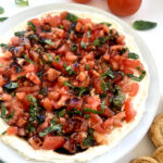 Bruschetta Dip next to tomatoes, basil, and crostinis