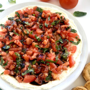 Bruschetta Dip next to tomatoes, basil, and crostinis