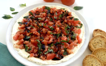 Bruschetta Dip next to tomatoes, basil, and crostinis