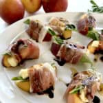 Peach and Prosciutto Appetizers on a white platter with peaches in background