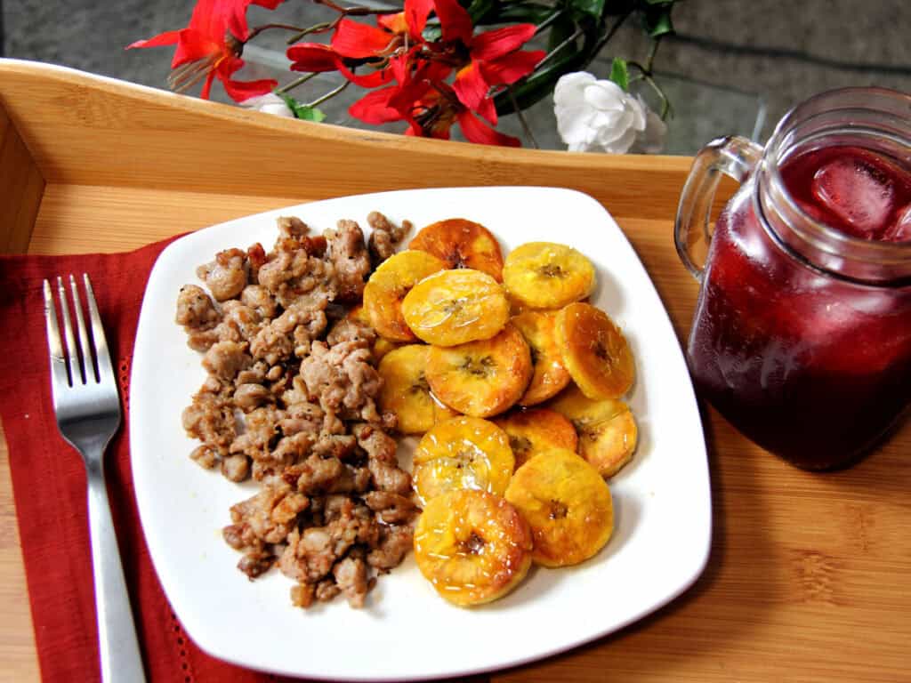 Ground sausage and fried plantains served with unsweet fruity black tea in mason jar.