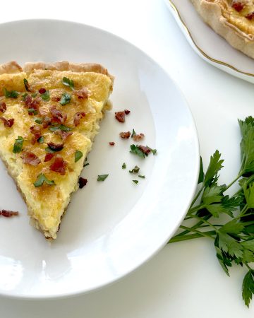 Gluten Free Quiche Lorraine on plate with parsley and quiche plate next to it
