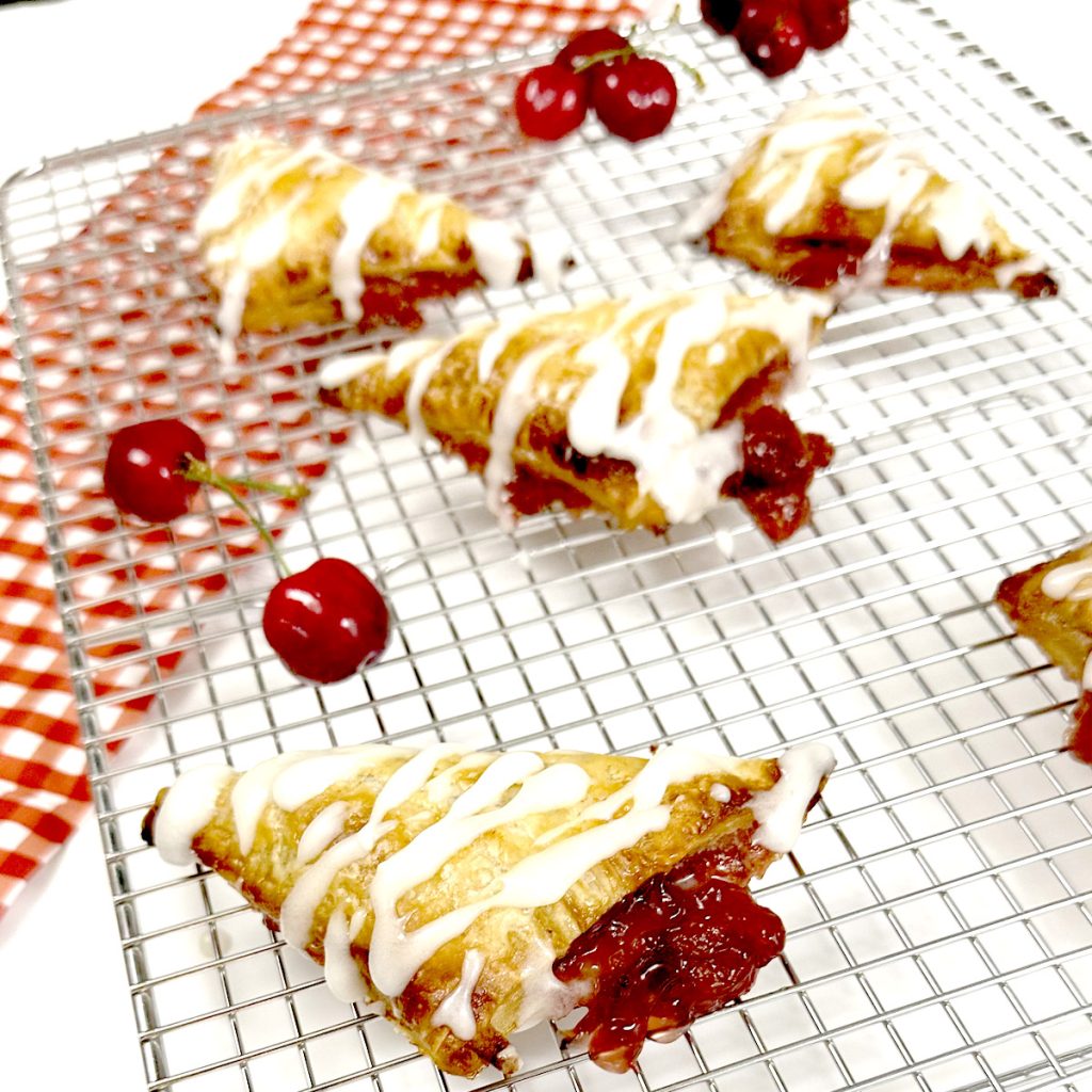 Gluten Free Cherry Turnovers on Baking Cooling Rack next to cherries