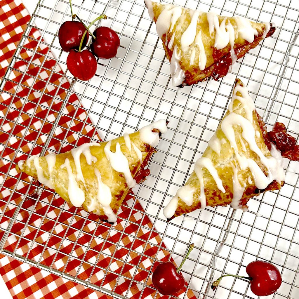 Gluten Free Cherry Turnovers on Baking Cooling Rack next to cherries