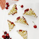 Gluten Free Cherry Turnovers on white parchment paper next to cherries