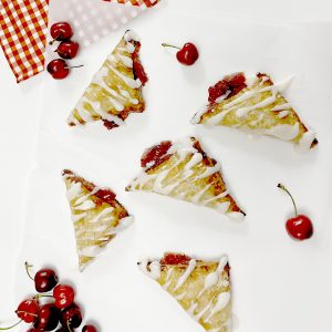 Gluten Free Cherry Turnovers on white parchment paper next to cherries