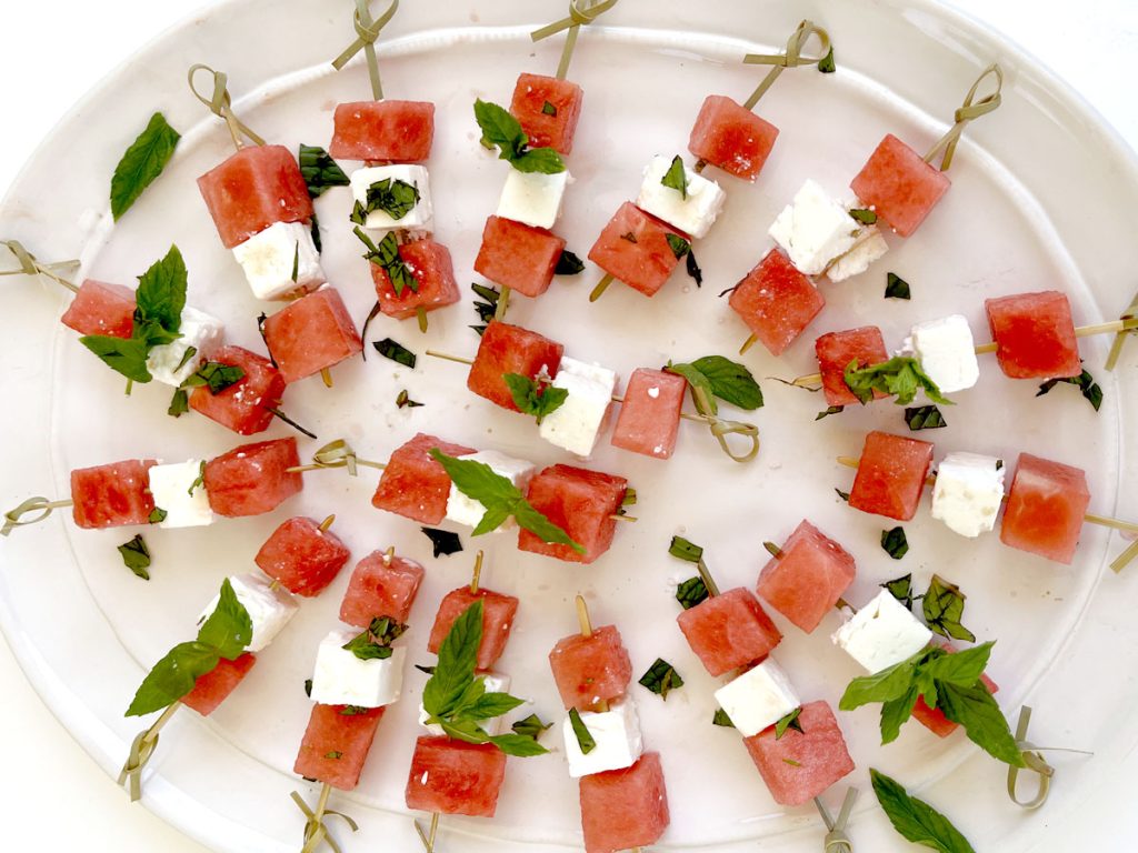 Watermelon Basil Feta Skewers on White Platter with Bright Blue Background